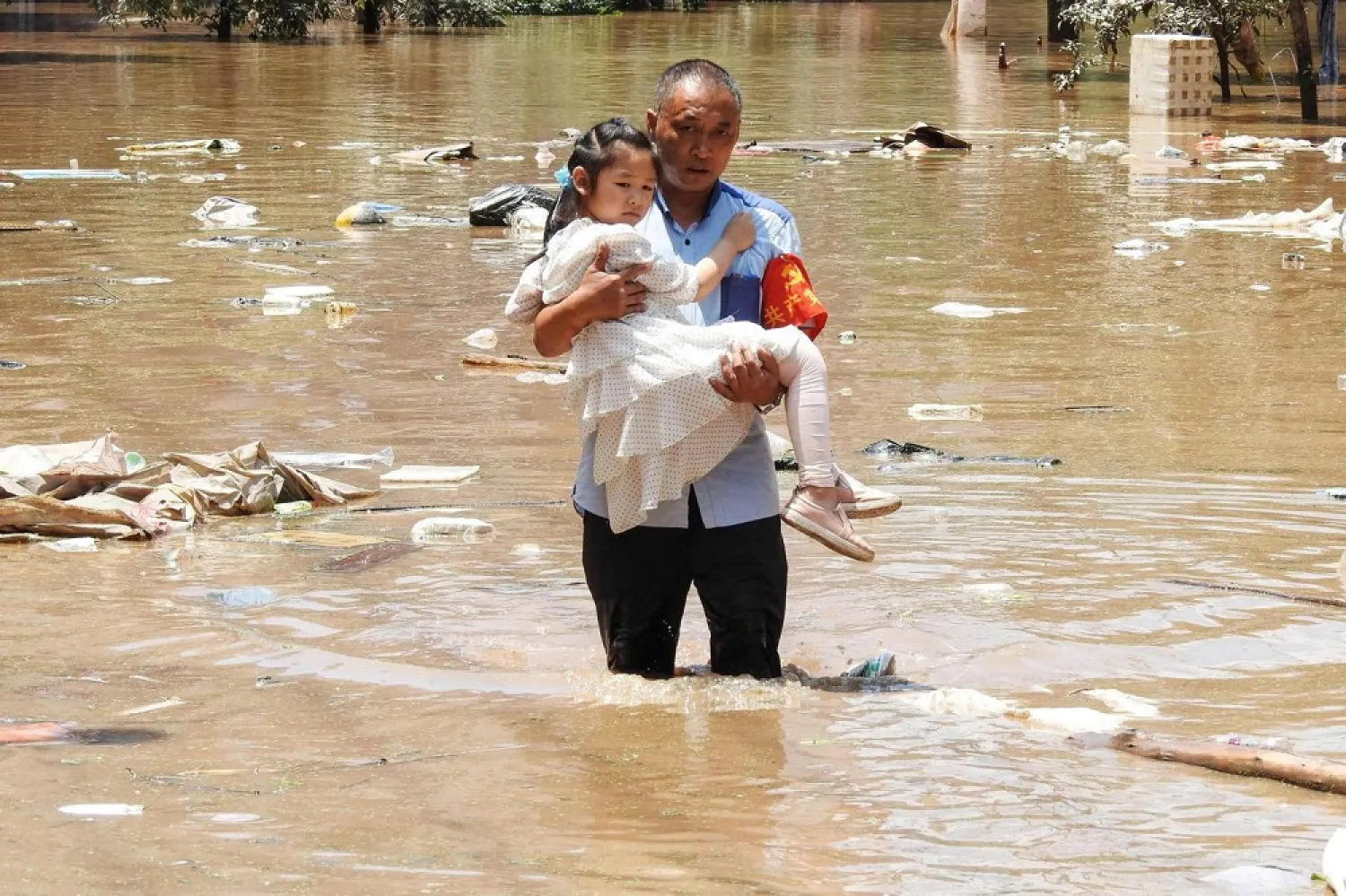 A village official evacuating a child from a flooded area following heavy rains in Dazhou, Sichuan province, on July 12, 2021. (AFP)