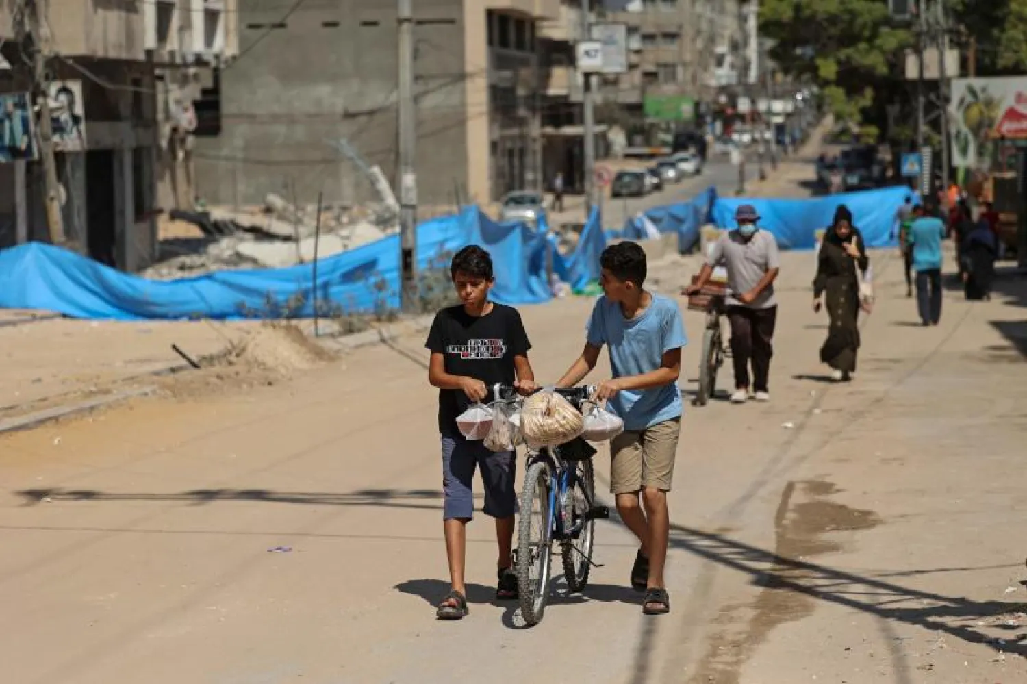 أطفال فلسطينيون يسيرون بدراجاتهم على طول حي مطوق في غزة (أ.ف.ب)