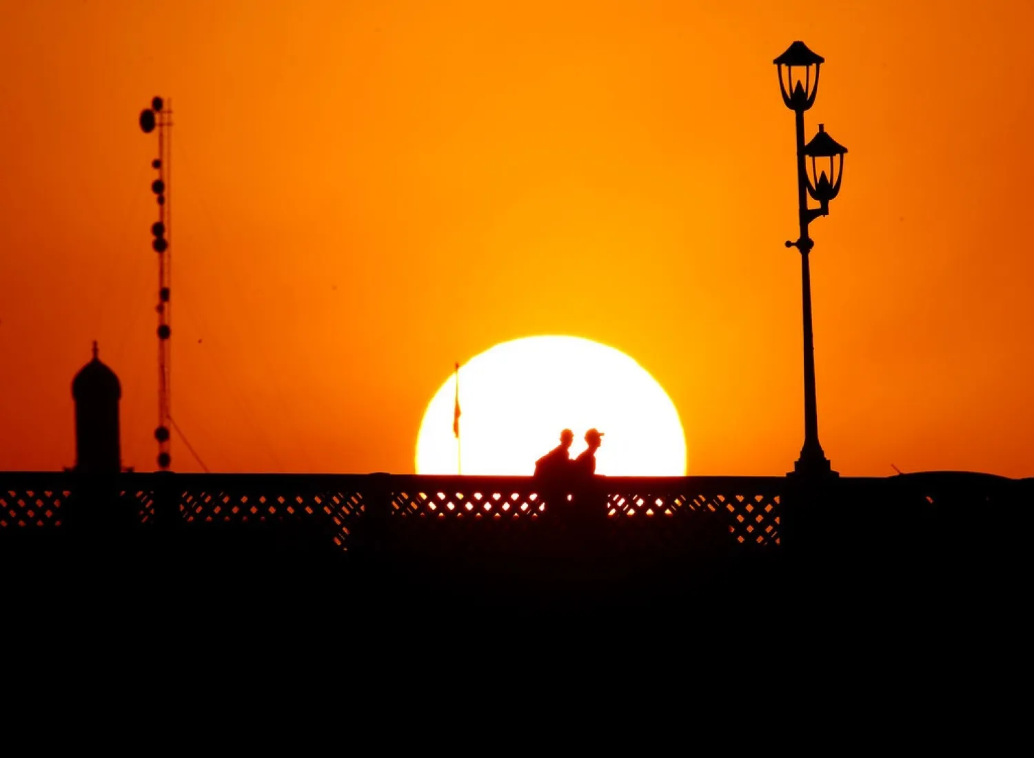 People crossing a bridge over the Tigris River as the sunsets in Baghdad on June 19, 2021. (AP)