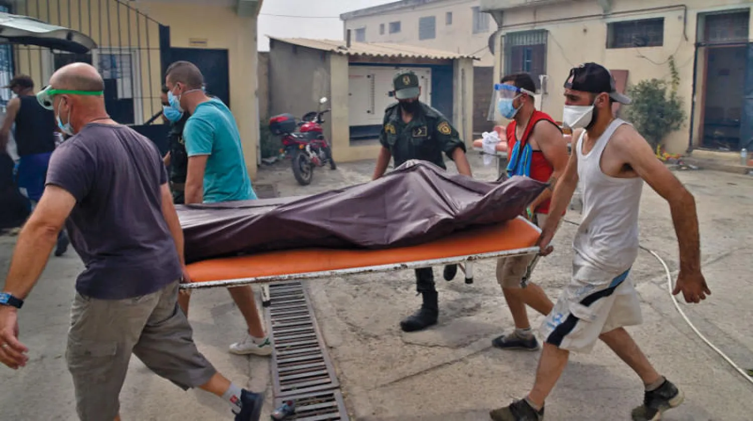 ممرضون يقومون بنقل أحد ضحايا حرائق تيزي وزو (أ.ف.ب)