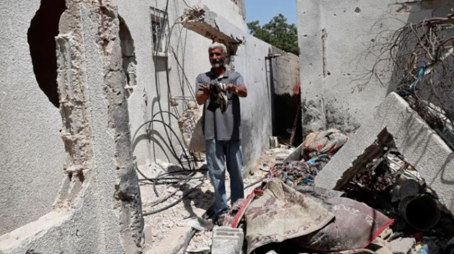 Geçen Mayıs ayında Gazze'de Hamas ile İsrail arasında yaşanan 11 günlük savaşta yıkılan evinin enkazında gezen bir adam (AP)