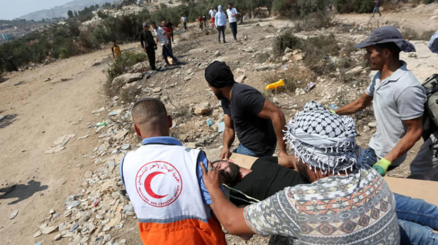 إنقاذ متظاهر أصيب في مواجهات مع الأمن الإسرائيلي احتجاجاً على بناء مستوطنة إيفياتار قرب نابلس (د.ب.أ)