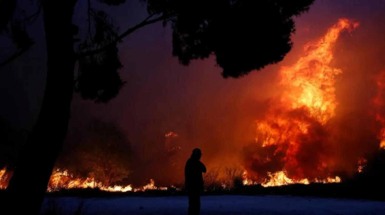 FILE: A man looks at the flames as a wildfire burns in the town of Rafina, near Athens, Greece, July 23, 2018. REUTERS/Costas Baltas