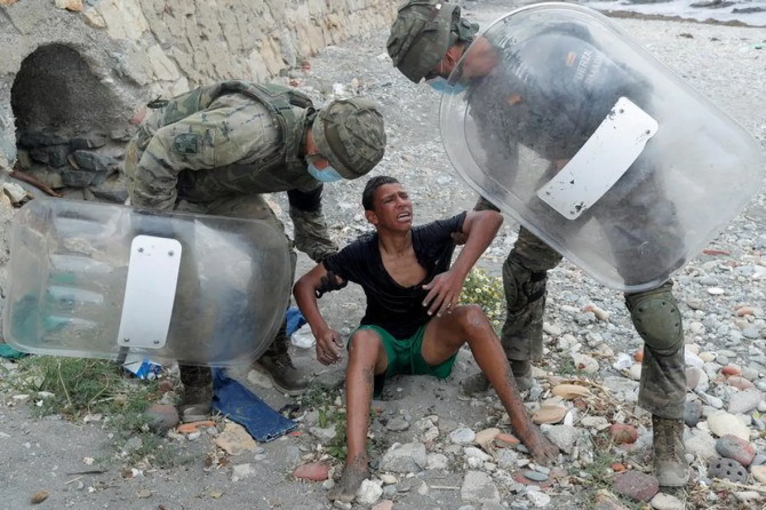 A Moroccan boy cries as he is helped by Spanish soldiers after he swam using bottles as a float, at El Tarajal beach, near the fence between the Spanish-Moroccan border, after thousands of migrants swam across the border, in Ceuta, Spain, May 19, 2021. REUTERS/Jon Nazca/File Photo/File Photo

