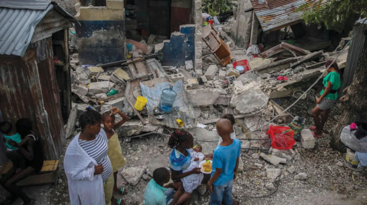 أسرة تتناول الإفطار في موقع انهيار منزلها بهايتي أمس (أ.ب)