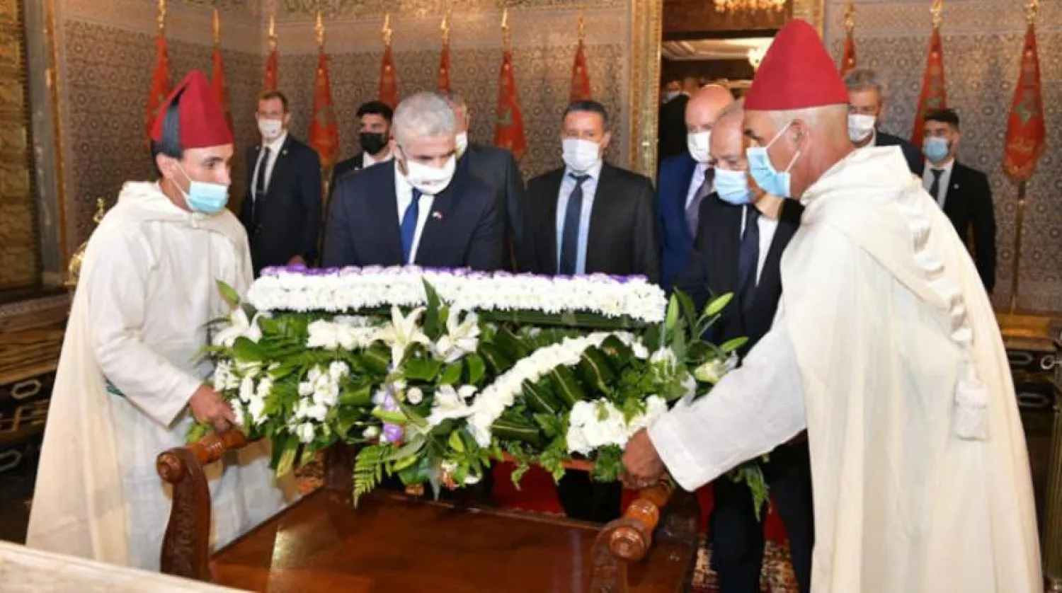 یائر لیپڈ (بائیں) کو مراکش کے مرحوم شاہ محمد پنجم کے مزار پر حاضری کے دوران پھولوں کا گلدستہ رکھتے ہوئے دیکھا جا سکتا ہے (رائٹرز)