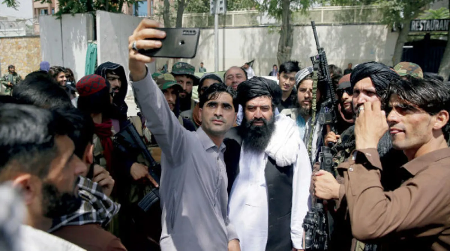 أفغاني يلتقط سيلفي مع مقاتلي {طالبان} في كابل أمس (أ.ب)