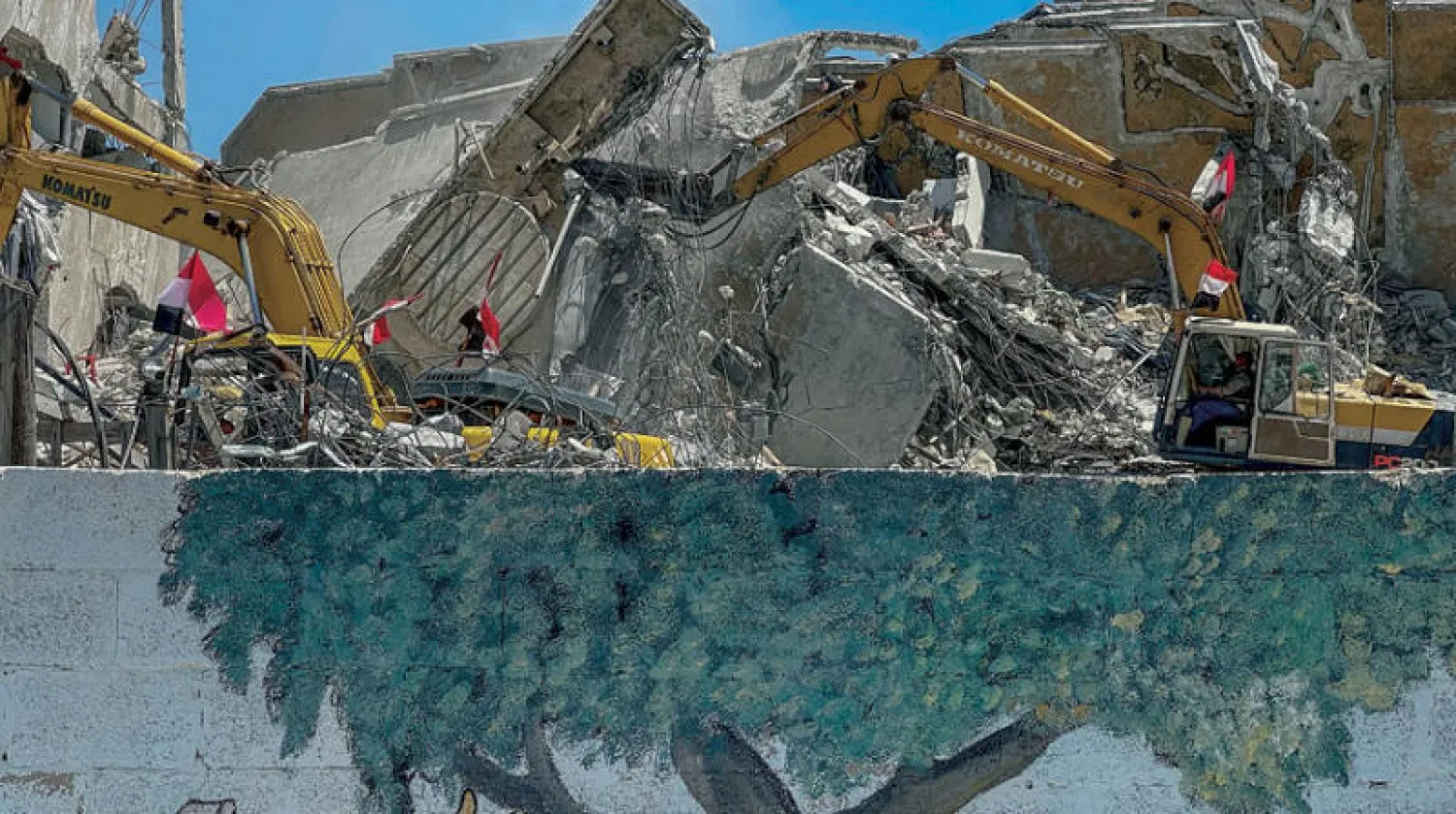 عمال مصريون مع معداتهم يزيلون أنقاض الأبراج والمنازل المدمرة في غزة (إ.ب.أ)