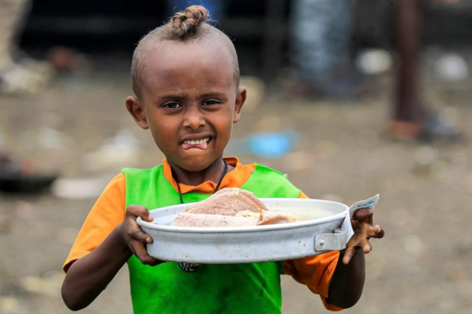 طفل من الكيمانت يحمل طعاماً في مخيم باسنقا (أ.ف.ب)