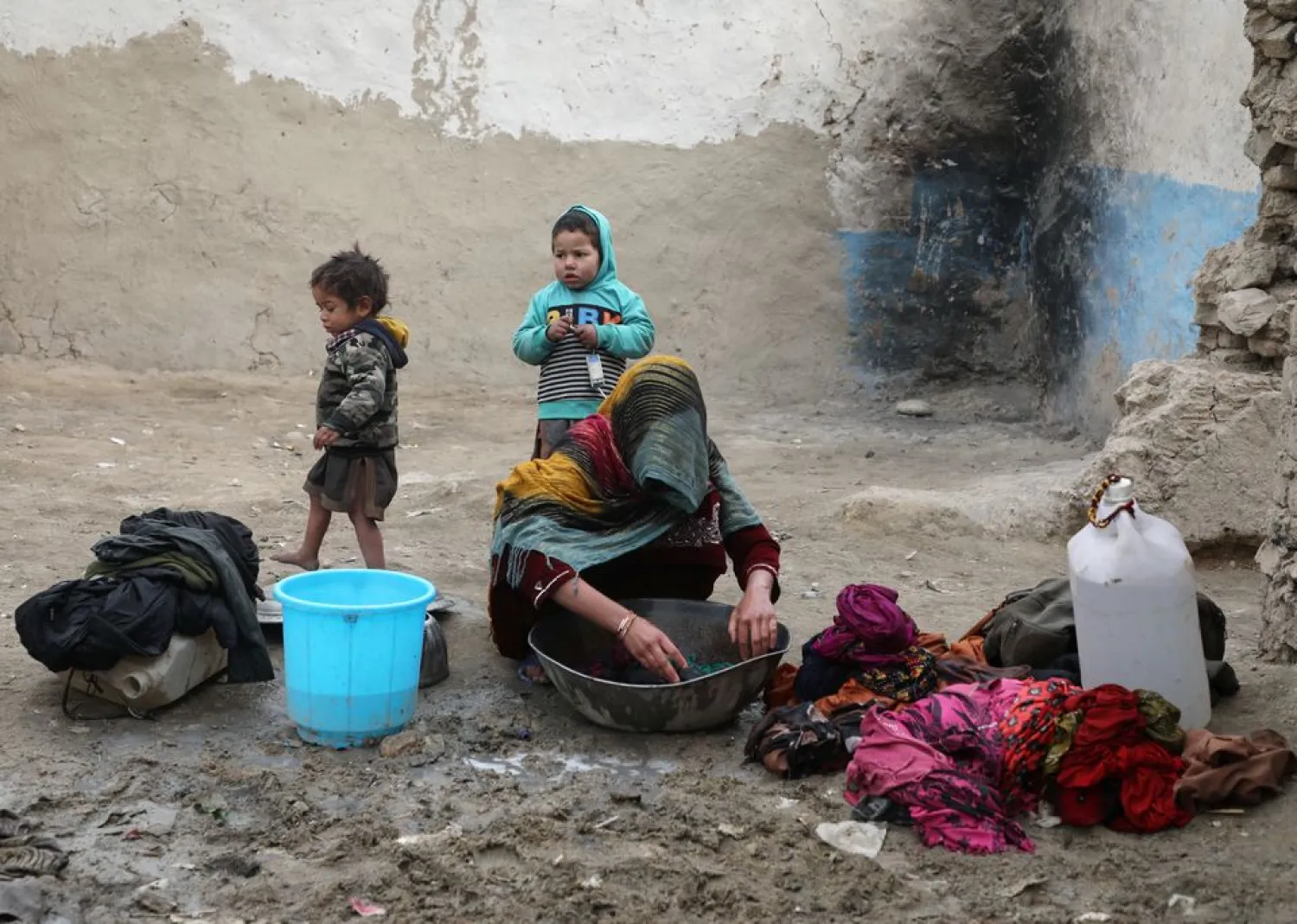 An internally displaced Afghan woman washes clothes outside her shelter on the outskirts of Kabul, Afghanistan February 3, 2021. (Reuters)