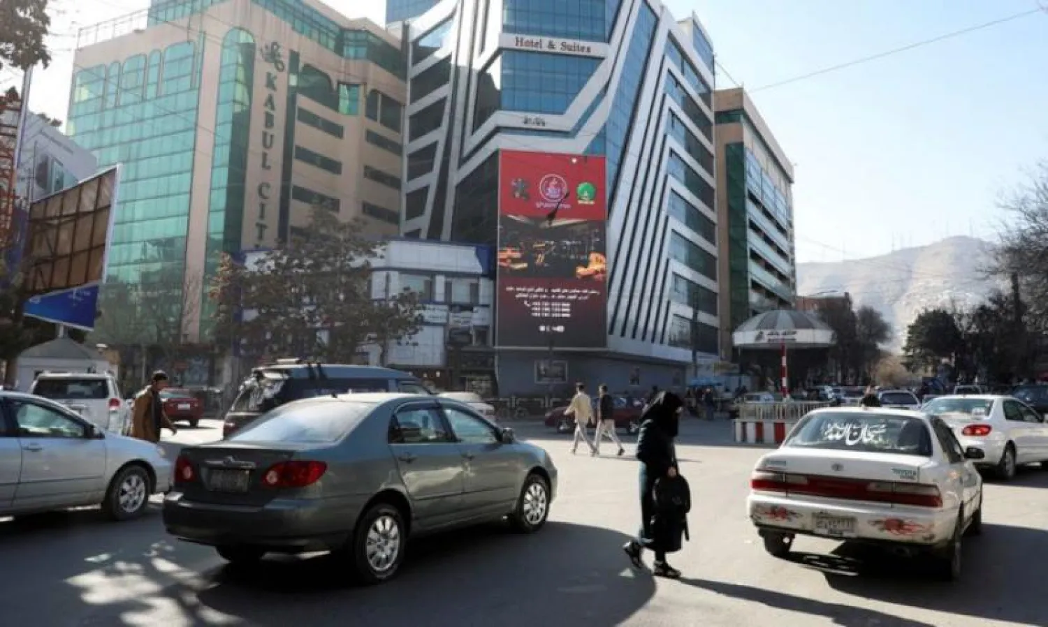 أشخاص يمشون أمام أحد البنوك في العاصمة كابل فبراير الماضي (أرشيفية - رويترز)