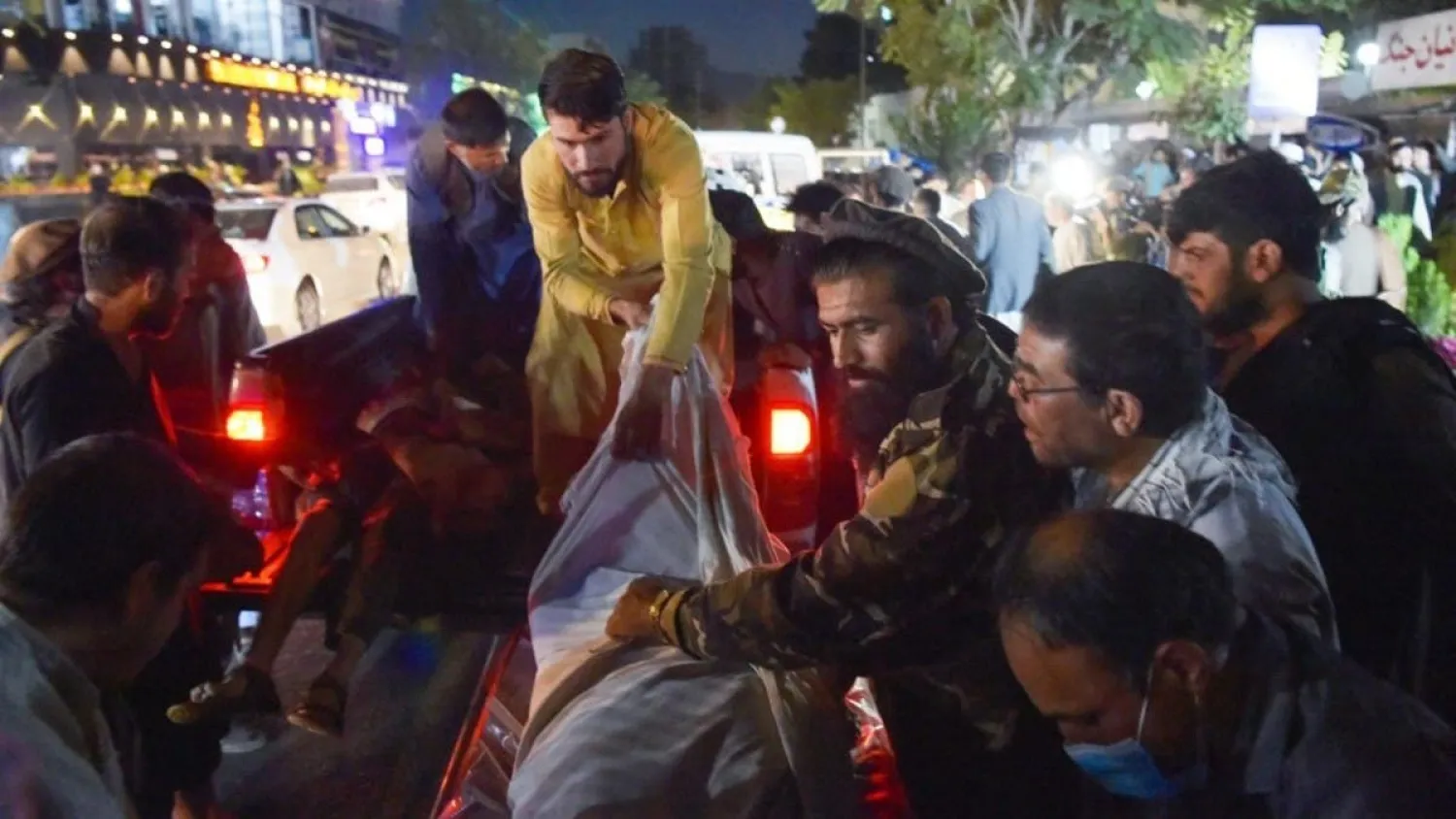 Volunteers and medical staff unload bodies from a pickup truck outside a hospital after two powerful explosions outside the airport in Kabul on August 26, 2021. (AFP)