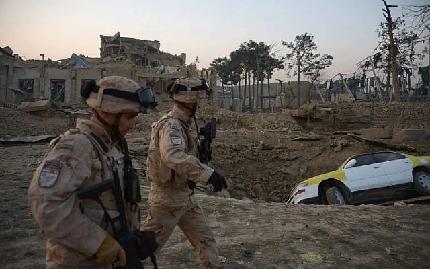 Croatian soldiers from the NATO coalition walk past a crater from a bomb blast as they inspect the site of an attack targeting the German consulate in Mazar-i-Sharif, Afghanistan on November 11, 2016. (AFP/Farshad Usyan)