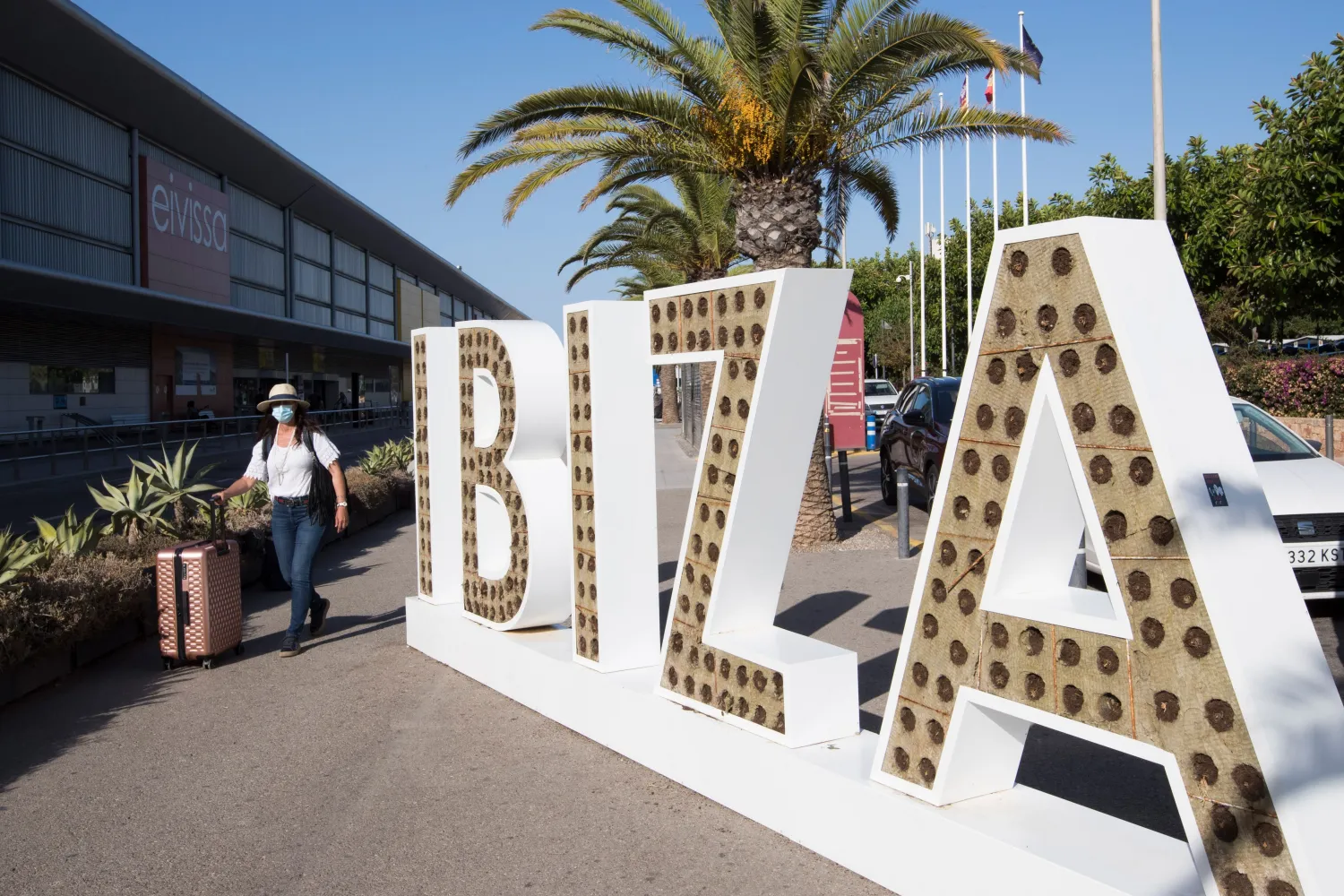 A tourist walks with her suitcase outside the airport in the Spanish island of Ibiza on July 30, 2020. AFP