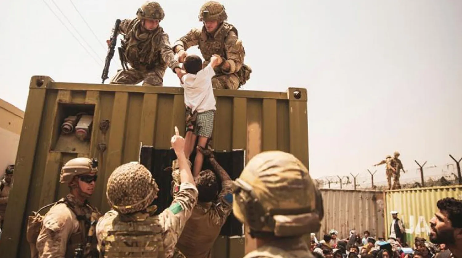 Kabil Havaalanı’ndaki tahliyeler sırasında, kontrol noktasında Afgan bir çocuğu taşıyan ABD askerleri (Reuters)