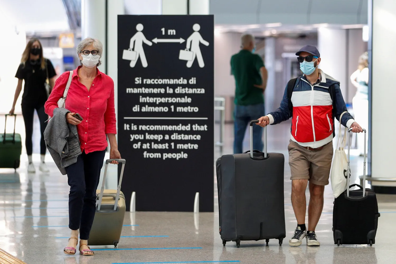 Passengers wearing protective face masks walk at Fiumicino Airport on the day EU governments agreed a "safe list" of 14 countries for which they will allow non-essential travel starting from July, following the coronavirus disease (COVID-19) outbreak, in Rome, Italy, June 30, 2020. REUTERS/Guglielmo Mangiapane