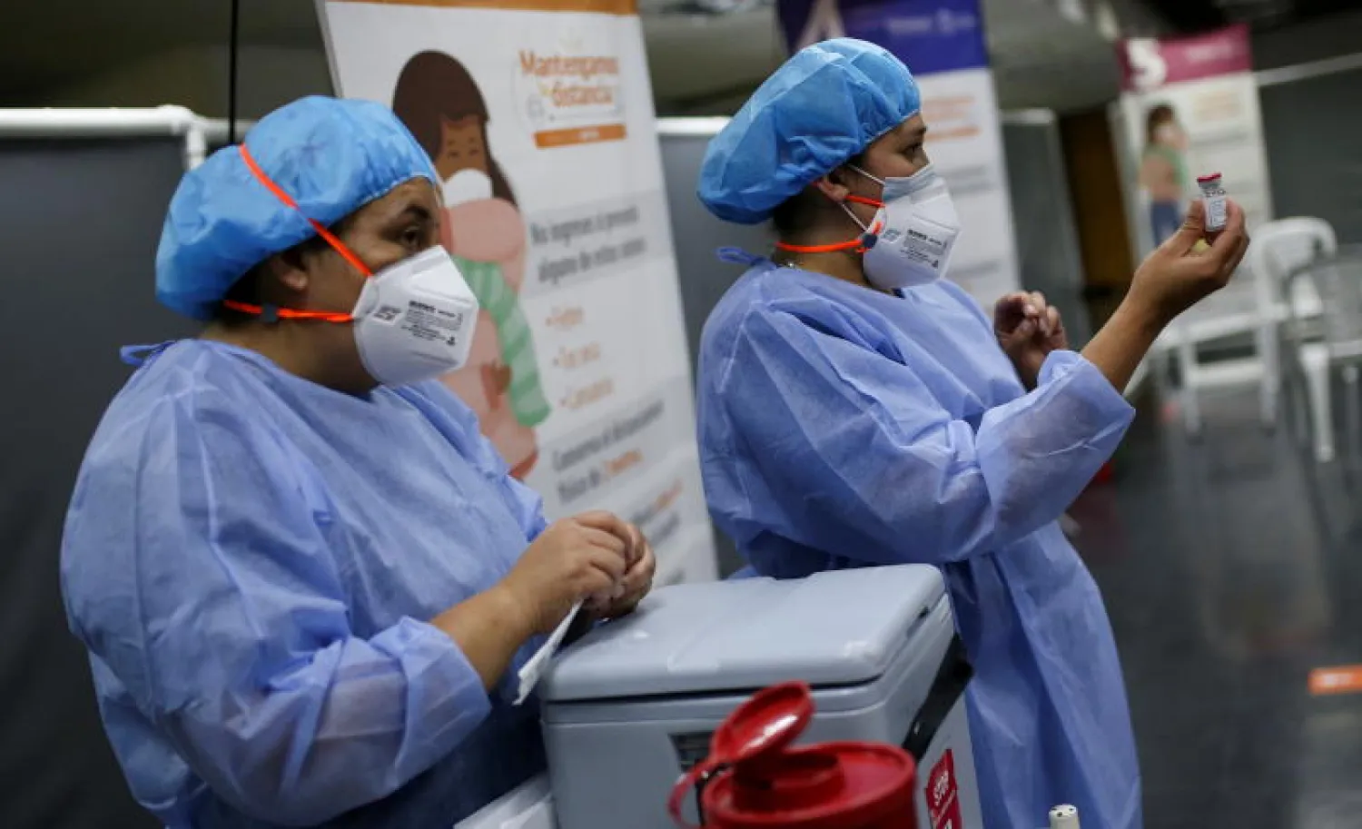 موظفتان صحيتان تشاركان في حملة التطعيم ضد فيروس كورونا بكولومبيا (رويترز)