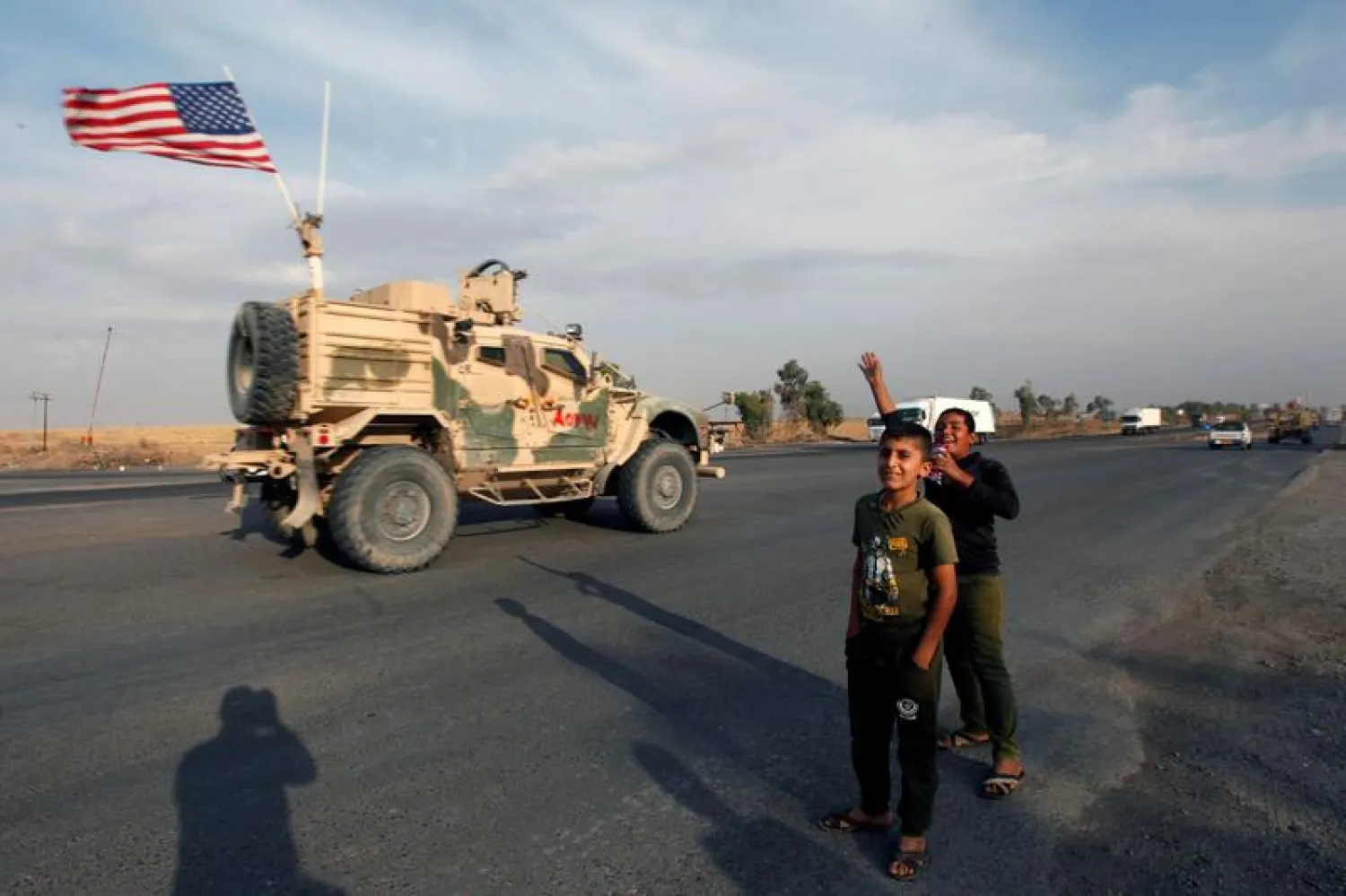 Boys wave towards a convoy of US vehicles withdrawing from northern Syria, in Erbil, Iraq October 21, 2019. (Reuters)