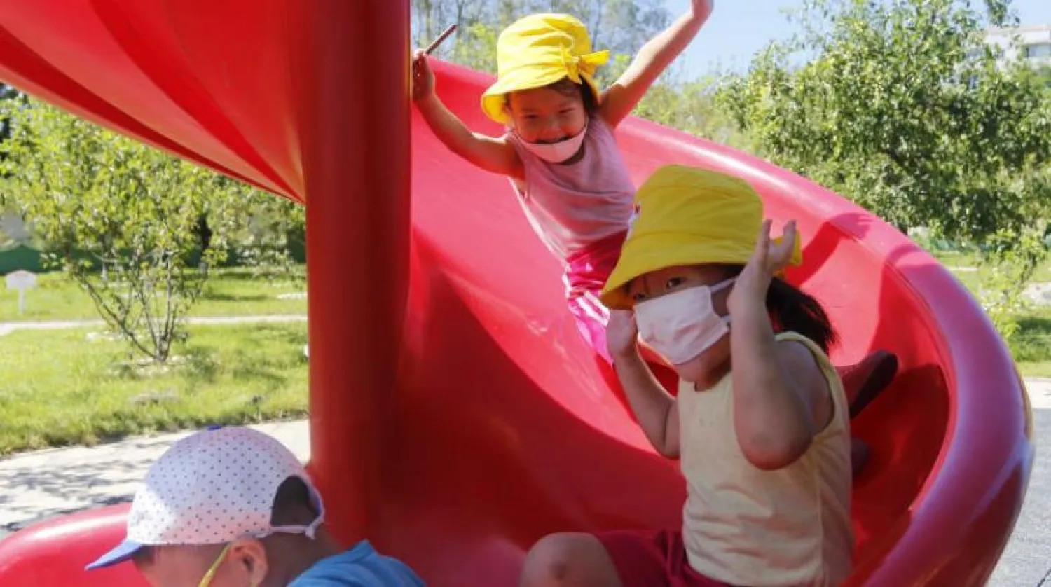 Kuzey Kore’de maskeleriyle parkta oynayan çocuklar (AP)