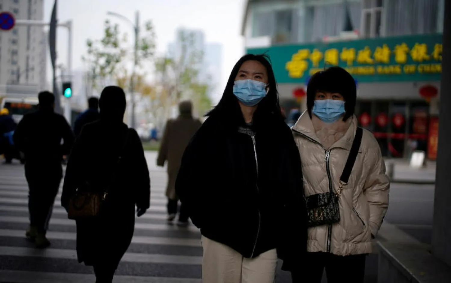أشخاص يضعون الكمامات في مدينة ووهان الصينية (رويترز)