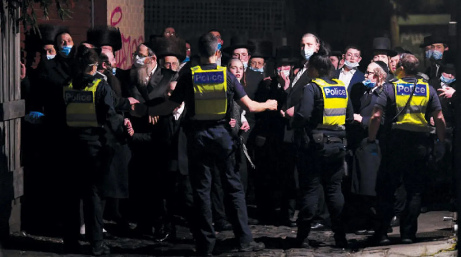 شرطيون أمام مبنى مجاور لكنيس يهودي يُشتبه أن مصلين تجمعوا فيه بشكل مخالف لإجراءات منع انتشار فيروس كورونا في مدينة ملبورن الاسترالية أمس (د.ب.أ)