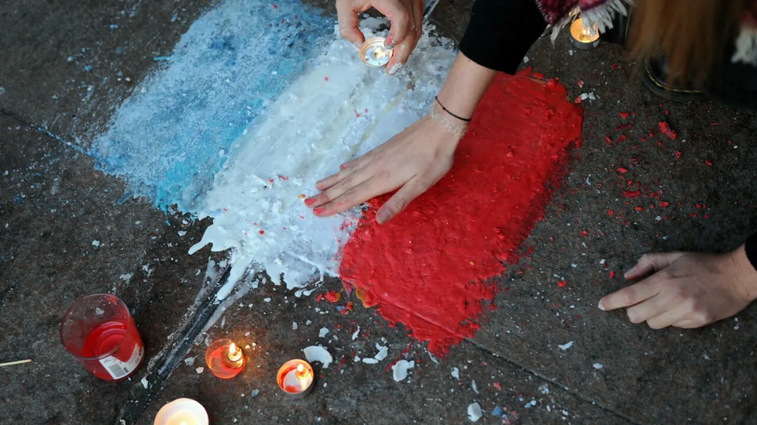 People light candles and draw a French flag in front of the town hall of Toulouse, on November 15, 2015, in tribute to the victims of the Paris attacks. (AFP)