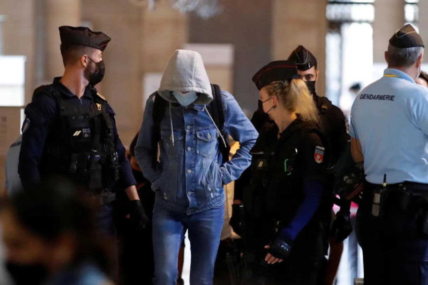 أفراد من الشرطة الفرنسية يرافقون متهماً في هجمات باريس 2015 لدى وصوله إلى المحكمة (رويترز)