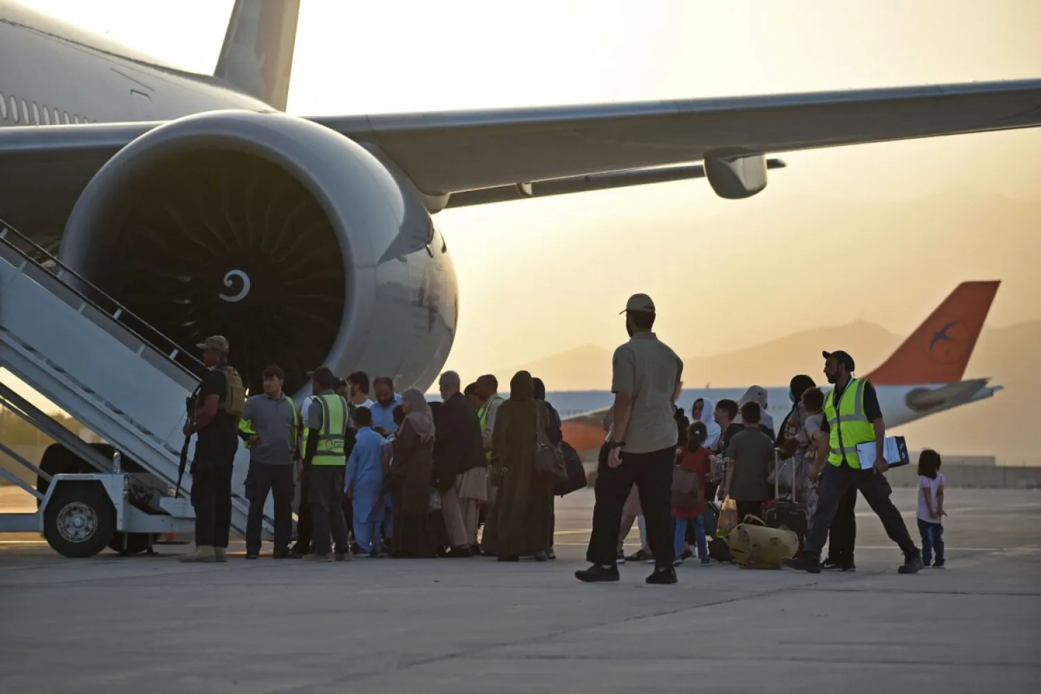 Passengers prepare to board a Qatar Airways aircraft at the airport in Kabul on September 9, 2021. (Photo by WAKIL KOHSAR / AFP)