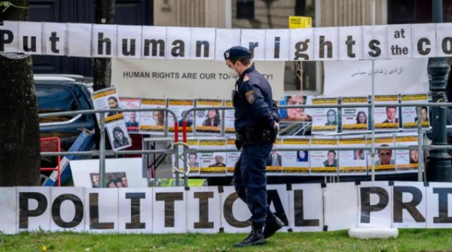 شرطي يحرس الفندق الذي يستضيف المفاوضات في فيينا بينما وضع معارضون إيرانيون لافتات ضد حكومة طهران (أرشيفية - أ.ف.ب)