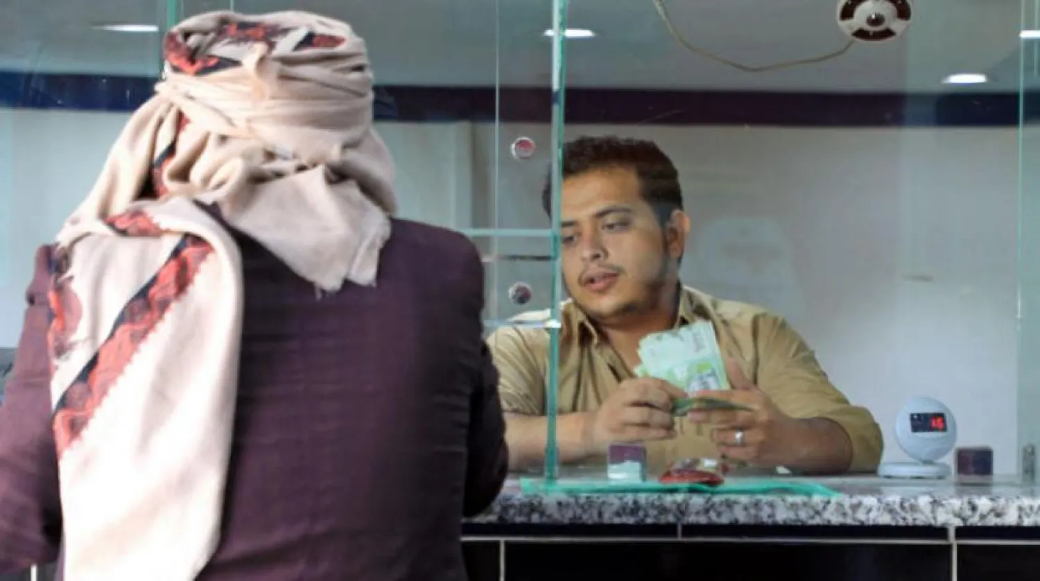 An employee providing services to a customer of an exchange store in Sana’a (AFP)