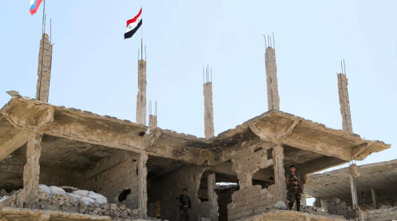 جنود قرب العلمين السوري والروسي في درعا البلد أمس (رويترز)