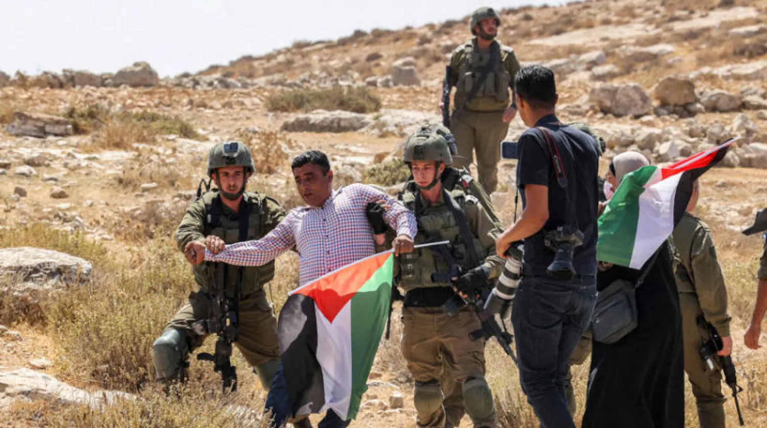 اعتقال فلسطيني يحتج ضد استيلاء مستوطنين إسرائيليين على أرضه جنوب الخليل (أ.ف.ب)