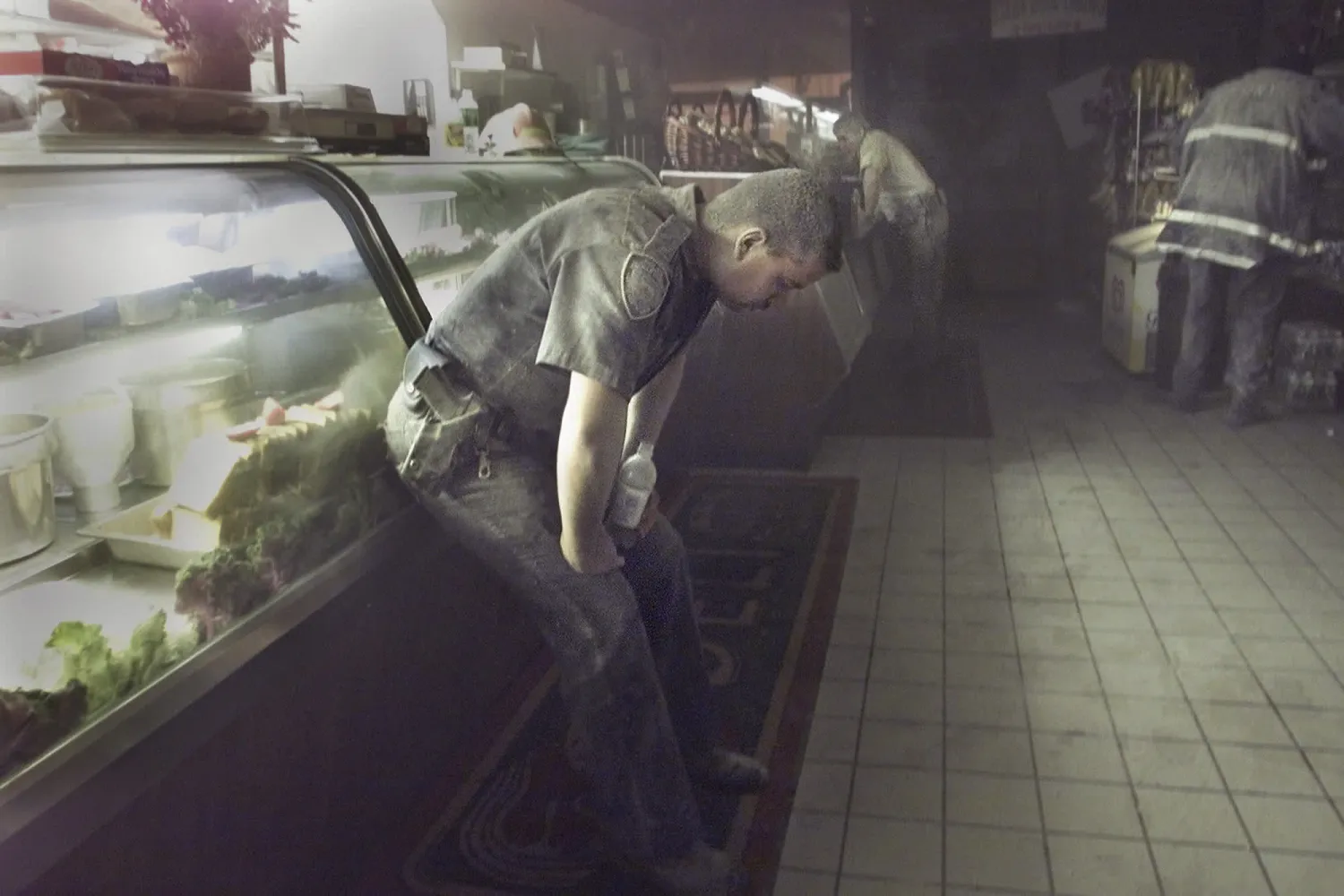 الشرطي ريتشارد أدامياك، في المقدمة، من بين العديد من الأشخاص الذين لجأوا إلى مطعم بالقرب من مركز التجارة العالمي بعد انهيار الأبراج «نيويورك تايمز»