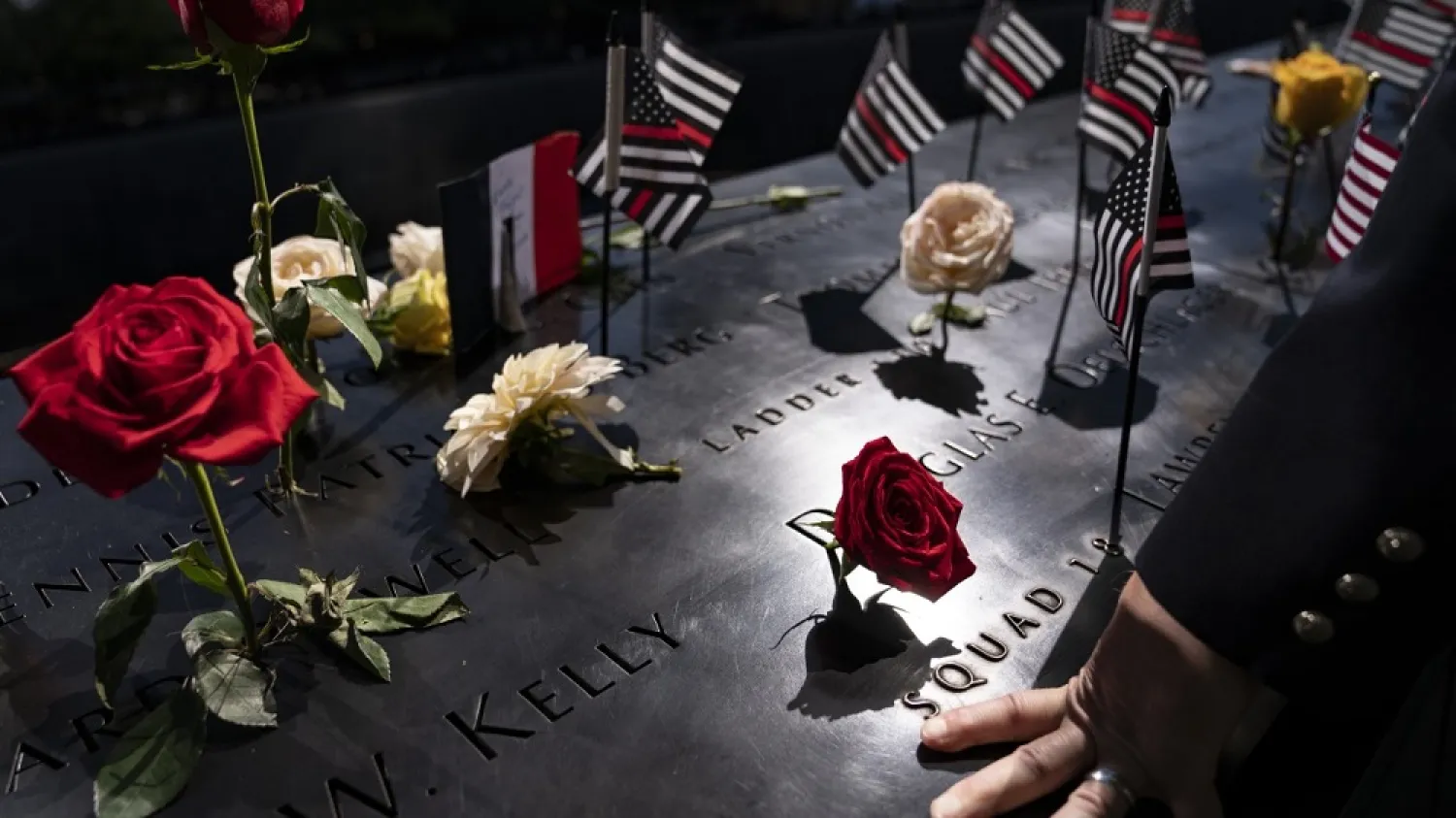 A firefighter places his hand on the name engravings on the south pool during ceremonies to commemorate the 20th anniversary of the Sept. 11 terrorist attacks, Saturday, Sept. 11, 2021, at the National September 11 Memorial & Museum in New York. (AP)