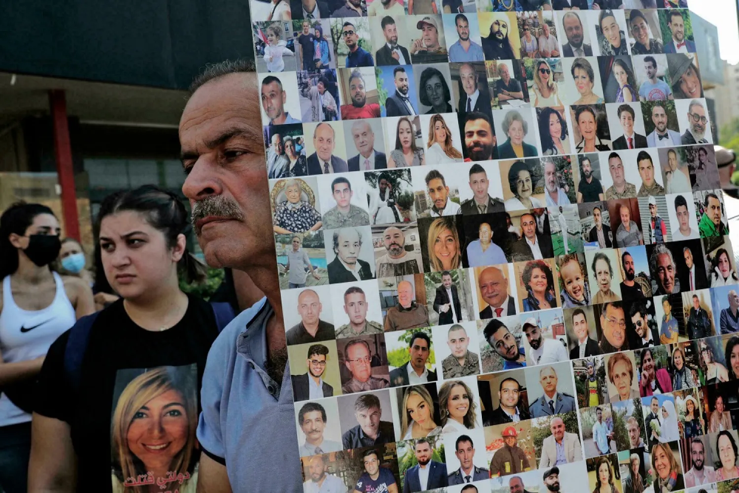 A man holds a sign showing Beirut port blast victims as protesters gather in the Lebanese capital on August 12, ahead of a parliamentary meeting on the blast investigation. (AFP)