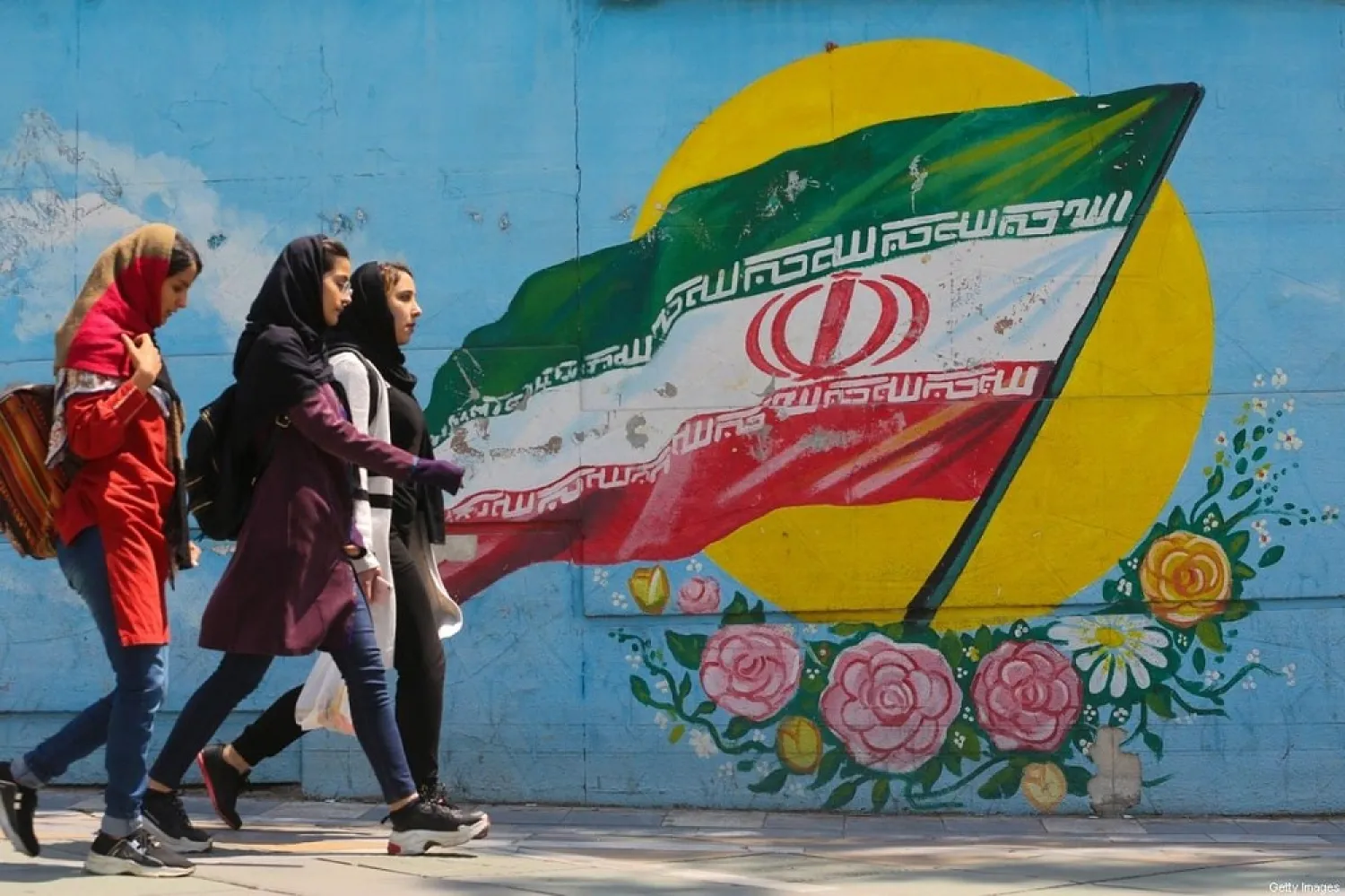 Young girls walk in front of a mural showing the Iranian national flag in Tehran, Iran on April 23, 2019. (Getty Images)