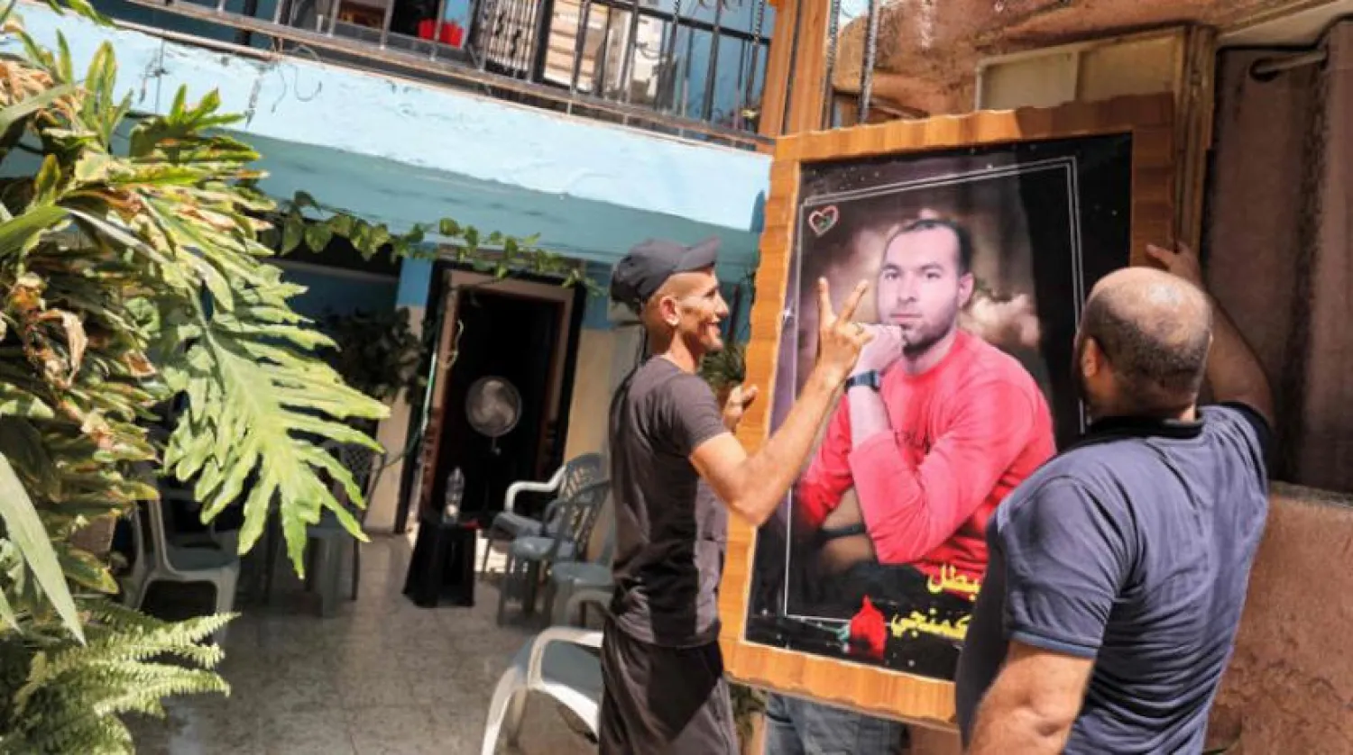 Family members of Ayham Kammaji, one of the six Palestinian prisoners, raise a picture of him at the family home in Kafr Dan, near Jenin (AFP)
