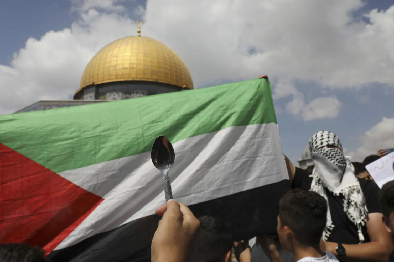 متظاهرون يحملون العلم الفلسطيني وملعقة بعد صلاة الجمعة في القدس (أ.ب)