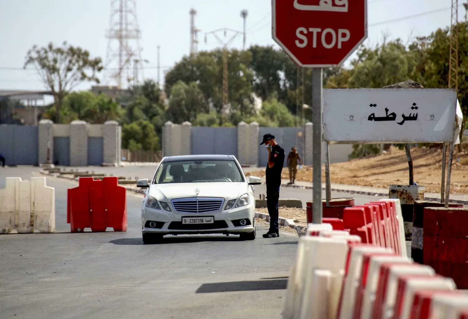 A Tunisian policeman checks a Libyan motorist at the Ras Jdeir border crossing between the two countries following its reopening after a two-month Covid closure. (AFP)