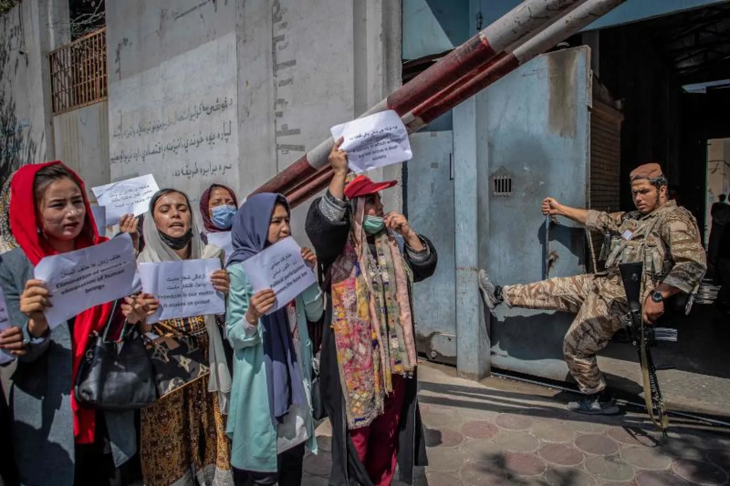 النساء الأفغانيات يتظاهرن أمام مقاتل من «طالبان» في محيط وزارة شؤون المرأة سابقاً (أ.ف.ب)