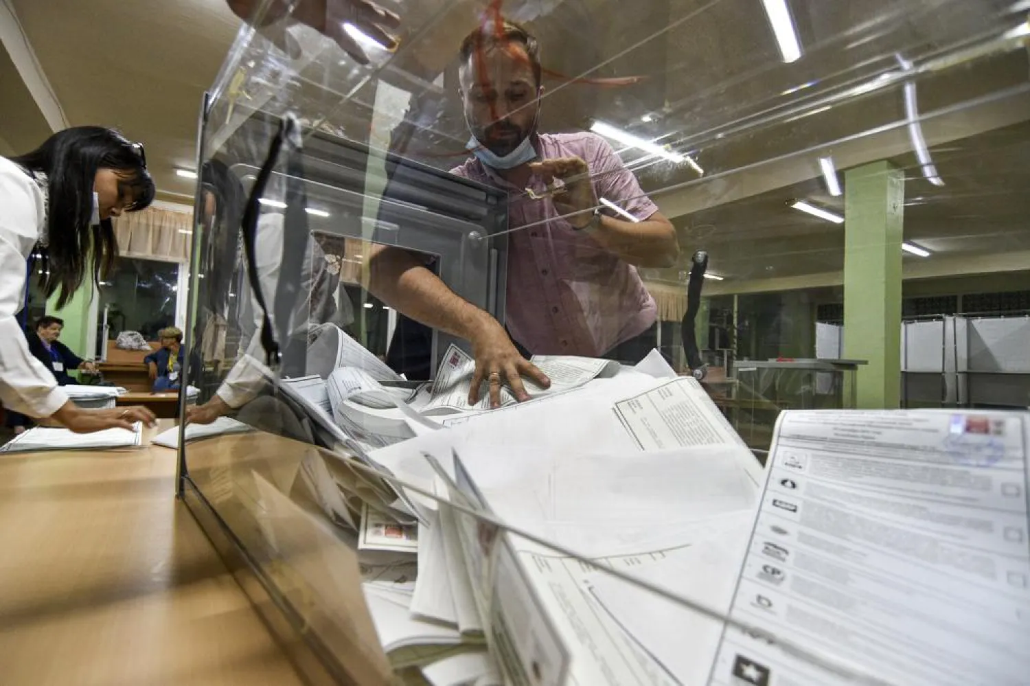 A member of an election commission pulls ballots out of a box preparing to count them at a polling station after the parliamentary elections in Nikolayevka in Bakhchysarai, Crimea, Sunday, Sept. 19, 2021. (AP Photo)
