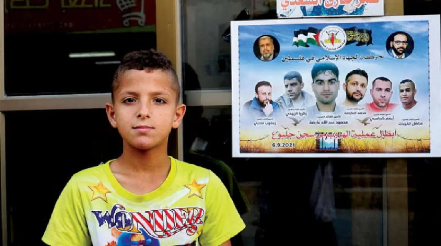 Cenin Kampı’ndaki bir duvarda altı mahkumun desteklendiği posterin yanında duran bir çocuk (AFP)