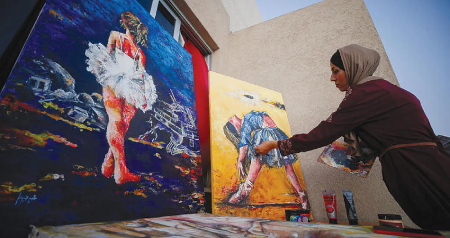 الفنانة عبير جبريل تعمل على لوحات باليه في منزلها بغزة (رويترز)