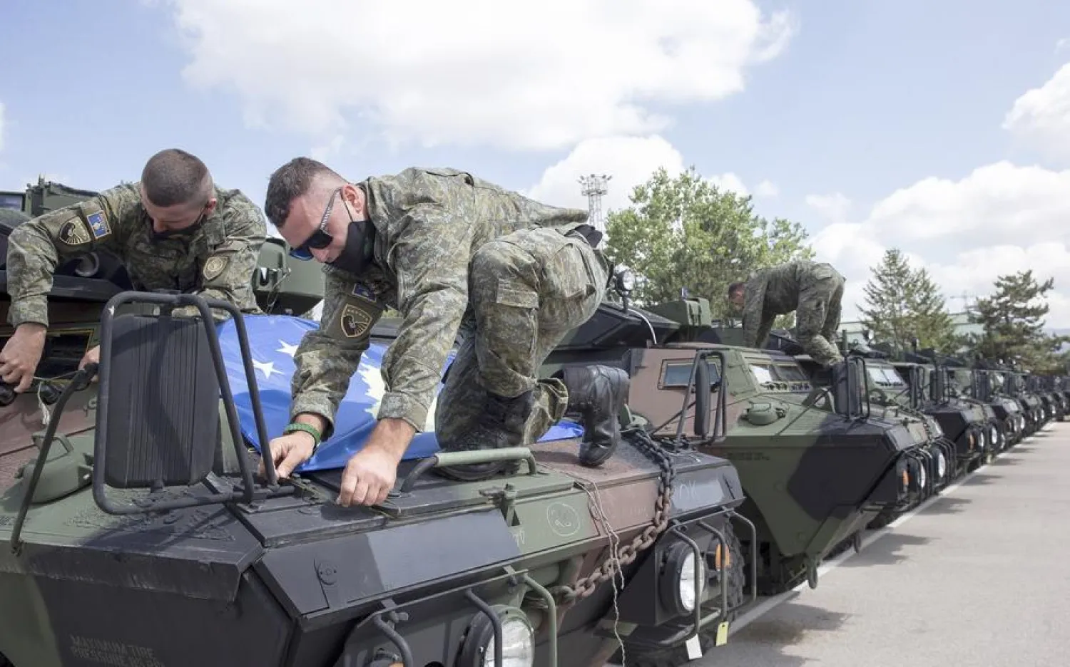 Kosovo Security Force soldiers place a Kosovo flag on top of armored security vehicle donated by US during a handout ceremony in the military barracks Adem Jashari in capital Pristina on Monday, Aug. 30, 2021. (Visar Kryeziu/AP)
