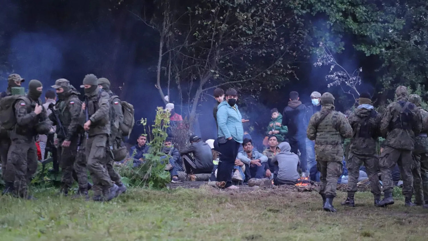 Polish border patrol officers guarding a group of people after they attempted to cross the Belarus-Poland border. /Grzegorz Dabrowski/Agencja Gazeta/via Reuters
