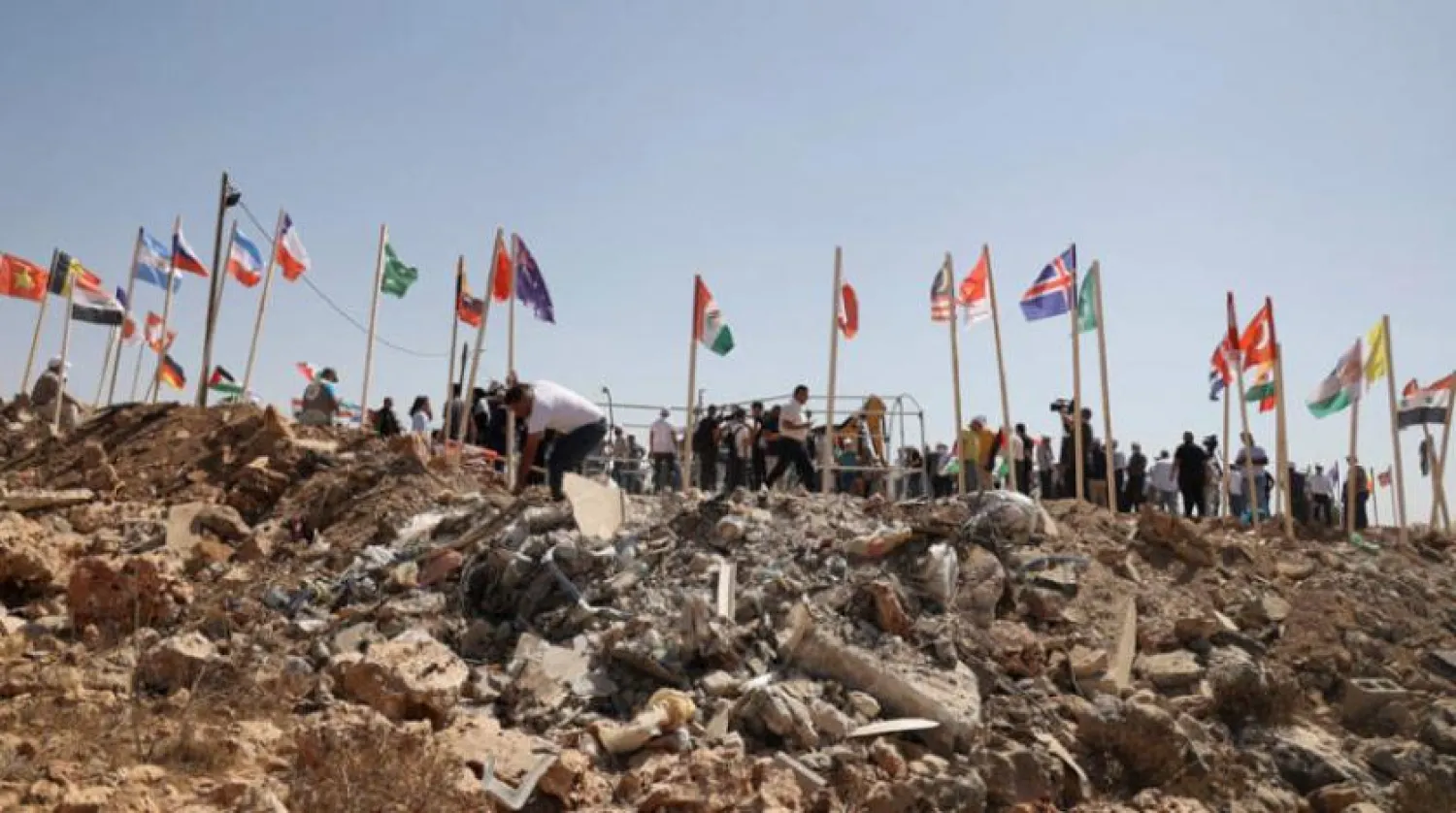 Filistinli göstericiler, yasadışı yerleşim birimlerini reddeden ülkelerin bayraklarını Batı Şeria'daki bir yerleşim bölgesi yakınların diktiler (AFP)