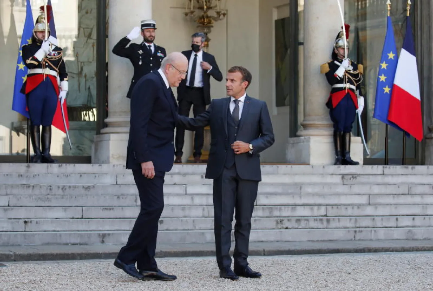 الرئيس الفرنسي إيمانويل ماكرون مودّعاً رئيس الوزراء اللبناني نجيب ميقاتي خارج قصر الإليزيه (رويترز)