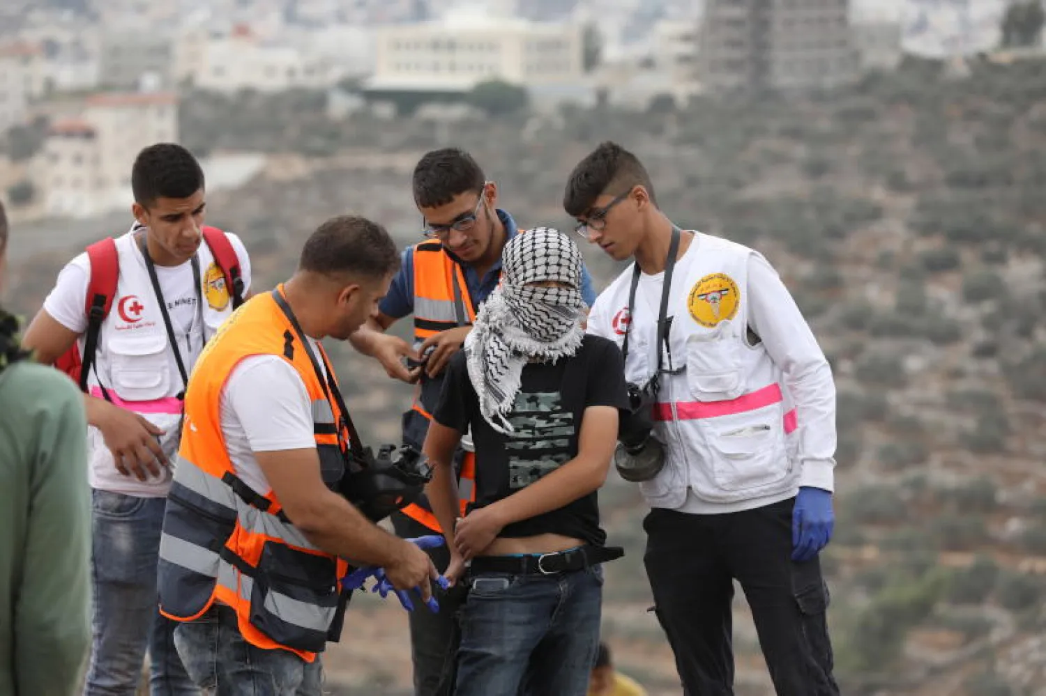 مسعفون فلسطينيون يساعدون جريحاً خلال المواجهات مع قوات الأمن الإسرائيلية قرب نابلس (إ.ب.أ)