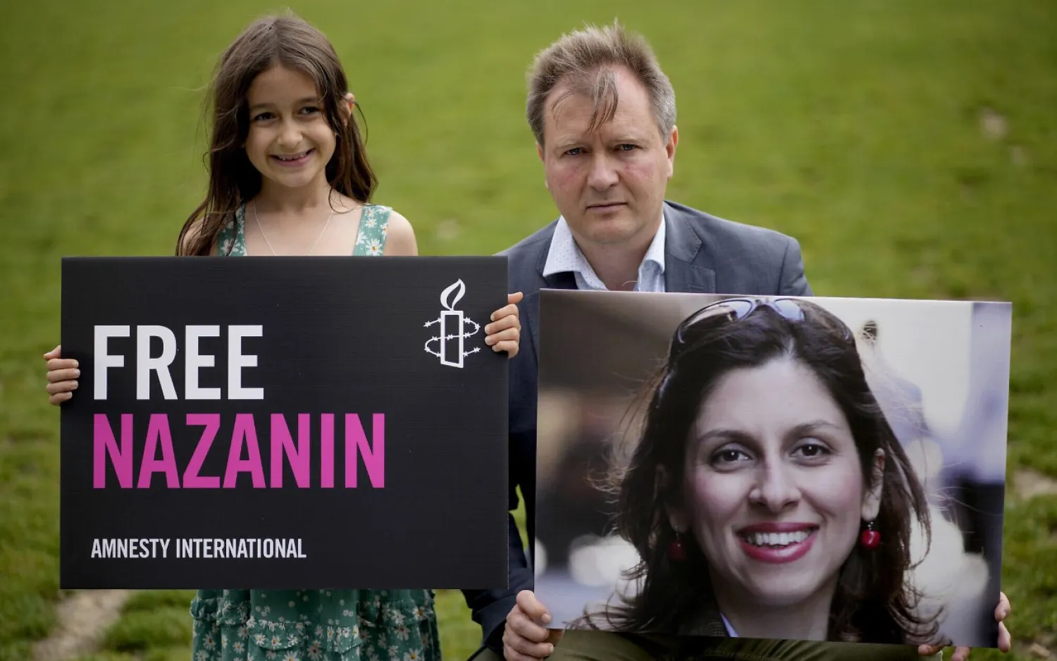 Richard Ratcliffe, the husband of imprisoned British-Iranian Nazanin Zaghari-Ratcliffe and their seven-year-old daughter Gabriella pose for the media backdropped by the scaffolded Houses of Parliament and the Elizabeth Tower, known as Big Ben, in Parliament Square, London, to mark the 2,000 days she has been detained in Iran, Thursday, September 23, 2021. (AP Photo/Matt Dunham)