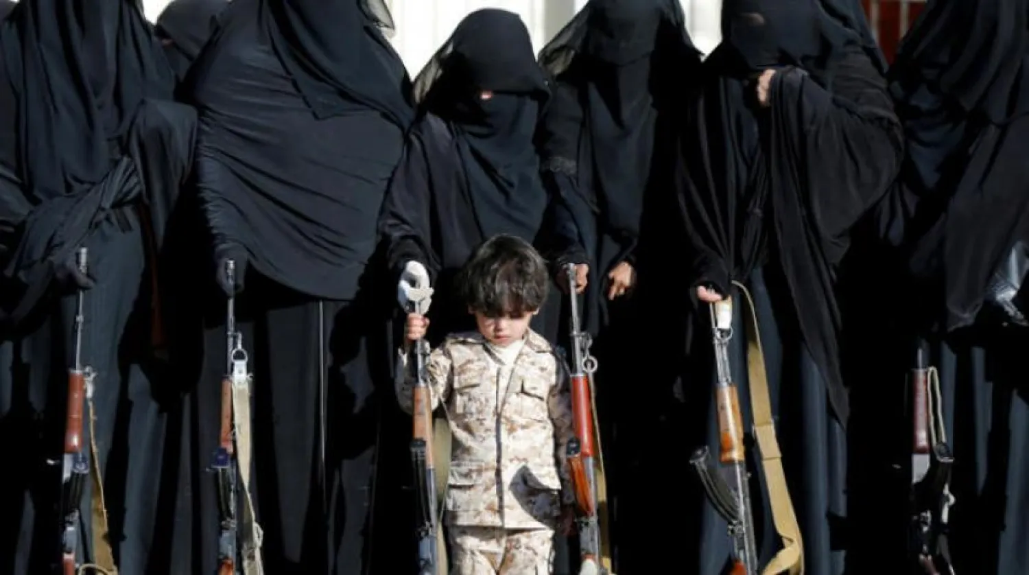 Child standing next to Houthi women in Sanaa at an armed gathering. Reuters